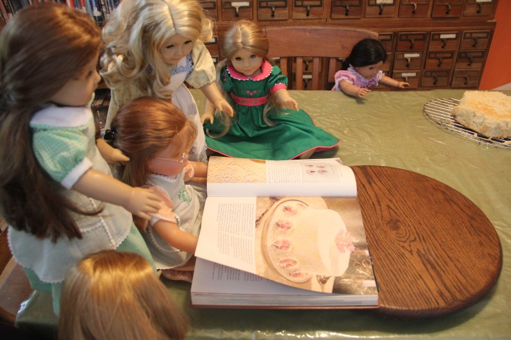 The dolls bake a cake on the "Stitching with Ellie" blog